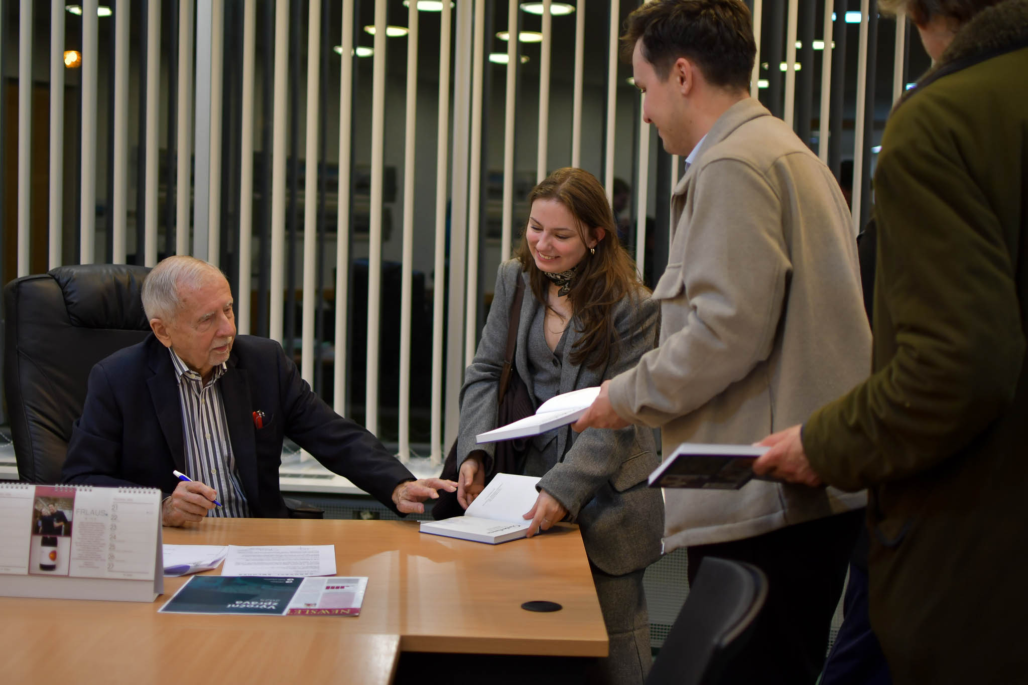 Na obrázku je ombudsman Křeček, který podepisuje svojí knížku s věnováním pro jednu z účastnic