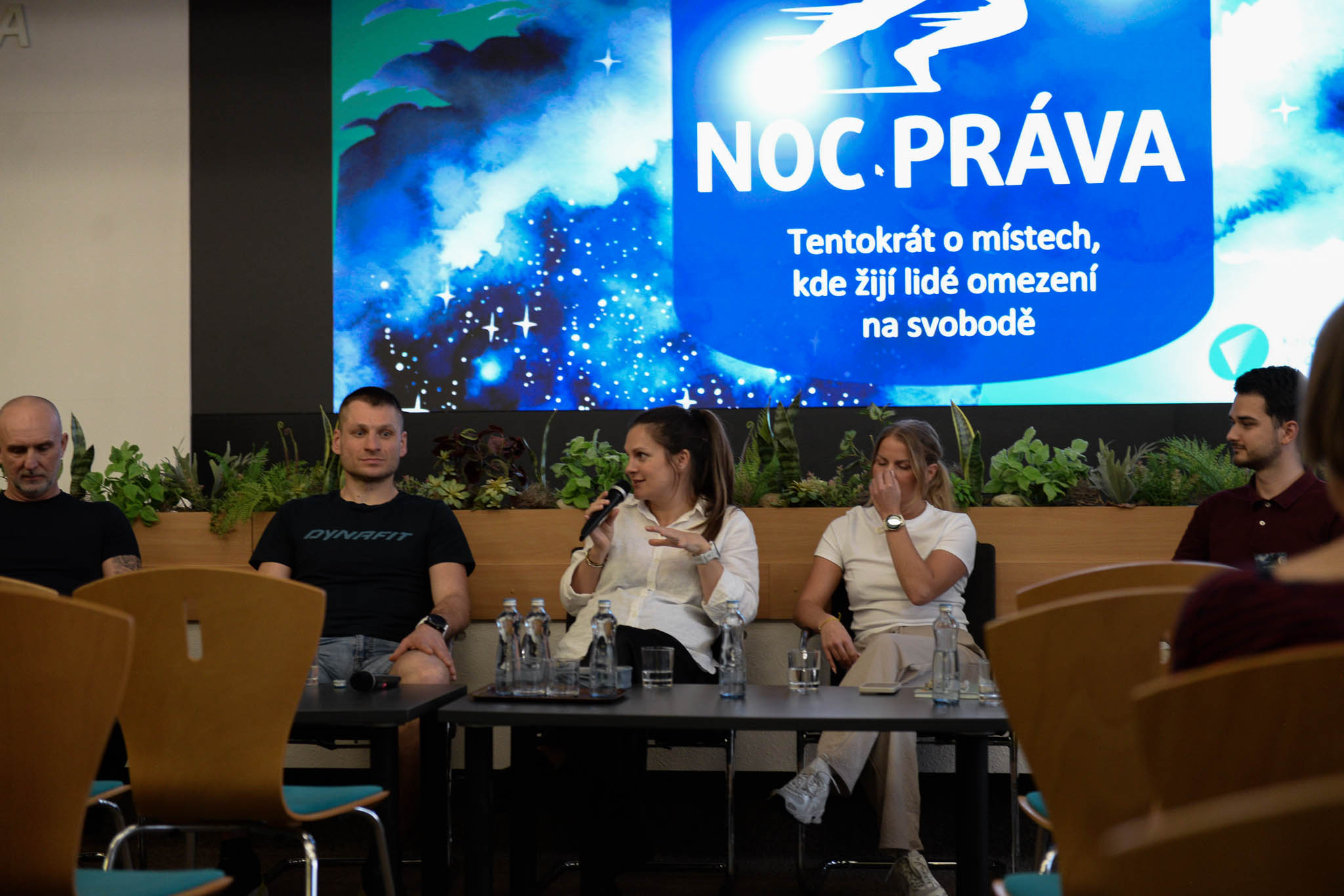 Na obrázku je režisérka dokumentu, která odpovídá na otázku v diskusi s protagonisty filmu. Za nimi je plátno.